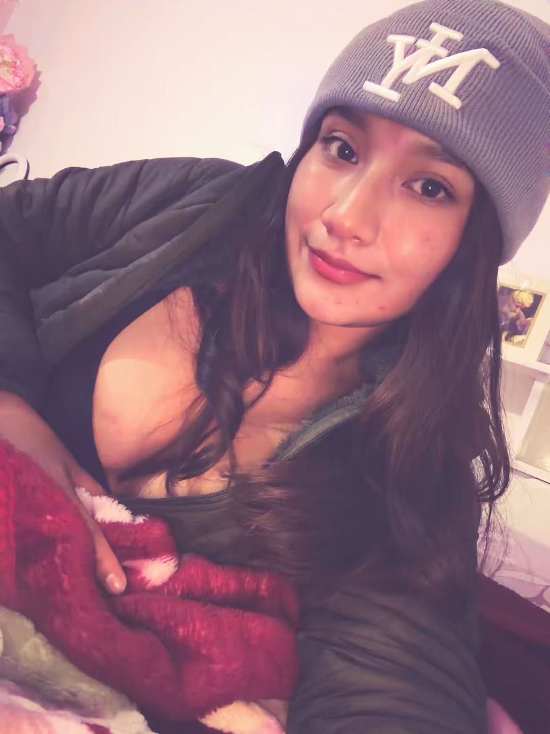 Abi🎀, BO — latina, dark hair, vertical half-body, grey beanie + puffer jacket on bed, cute soft smile