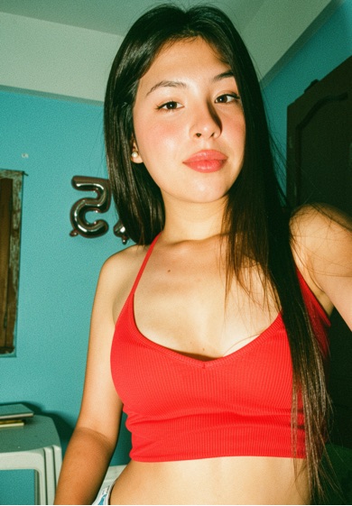 Amara, BO — latina, long dark hair, vertical half-body, red crop top, teal bedroom, soft smile